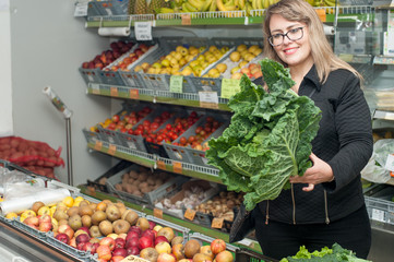 young blonde woman holding endive leaves in a grocery store.