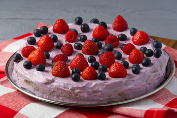 Home made Cheesecake with berries. Cheesecake with Strawberry, blueberry and raspberry on grey wooden background.