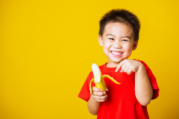 kid cute little boy attractive smile wearing red t-shirt playing holds peeled banana for eating