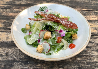 A plate of fresh caesar salad with crispy bacon and crispy bread