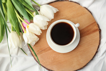 Cup of coffee and flowers on light background