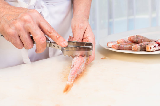 Hands Of Woman Flaking A Fresh Red Mullet