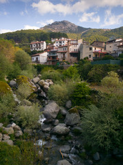 Fototapeta na wymiar La localidad abulense de Guisando en el valle del Tiétar, en pleno Parque Regional de la Sierra de Gredos. En primer término el río Pelayos y al fondo la Cabeza del Covacho (1.628 m).