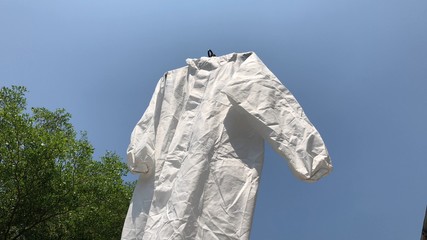 Protective PPE suit hanging outdoor after the used and washing,natural glare light,the ppe suit can...