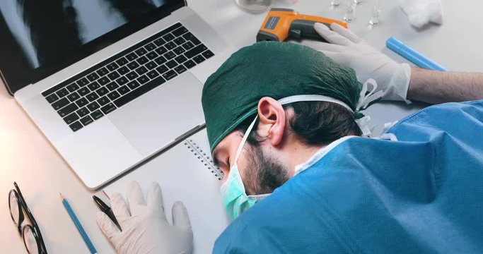 Medico o infermiere stanco dopo un turno estenuante nei reparti di Coronavirus, dorme sulla scrivania dell'ospedale.