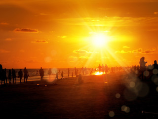group of silhouetted people on public beach over orange colored sunset sky in Siesta key, Sarasota, Florida