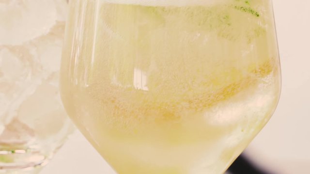 Pouring refreshing alcohol drink with bubbles, ice, lemon lime, gin tonic, soda. Close up shot.
