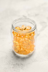 Jar with fish oil capsules on table