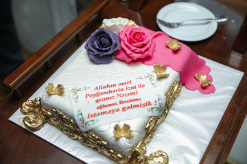 A white cake made for Hari . pink and purple cake . By God's command, with the permission of the Prophet, we have come to ask for your daughter for our son . A cake made for the engagement ceremony.