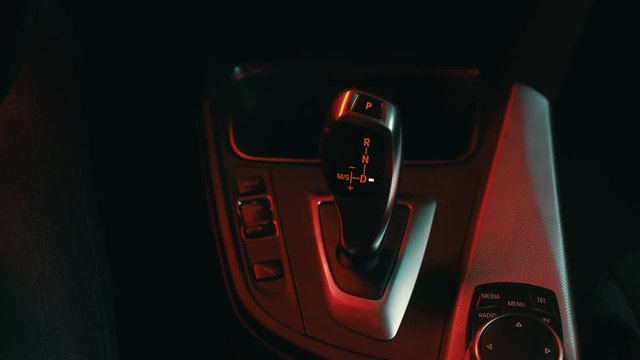 the man in the car puts hand the gear selector into drive mode