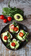 Healthy toasts with avocado and cherry tomatoes on a plate. Diet food at home.