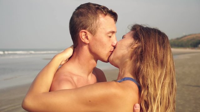 Young couple in love kisses on the beach. Newlyweds, honeymoon at sea
