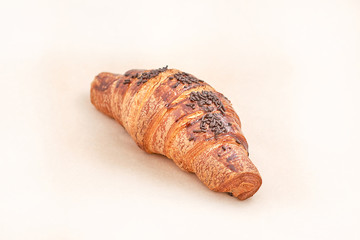 Croissant sprinkled with chocolate. Puff pastry. Closeup on a light background