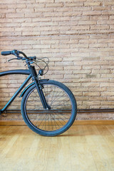 Vintage bicycle cafè-racer style in front of a brick wall with wooden ground