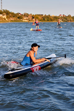 A Beautiful Girl Teenager Falling Off Stand Up Paddle Board SUP In The River At The Evening