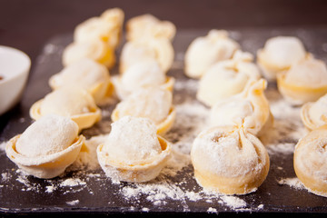Homemade uncooked russian pelmeni meat dumplings italian ravioli on cutting board.