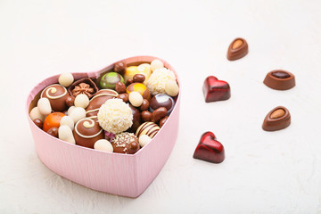Heart-shaped box with delicious candies on white background