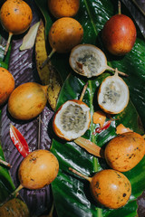 Close-up of yellow passion fruit and lychee fruit on banana leaves