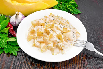 Pumpkin with sour cream sauce in plate on dark board