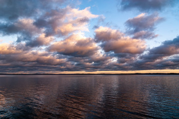 Dramatic clounds and sunset over the lake in Finland. Vanajavesi. Vanaja named Finnish lake near Hämeenlinna. Clear water, but storm rising upcoming in the horizon. 