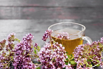 Tea of oregano in glass cup on board