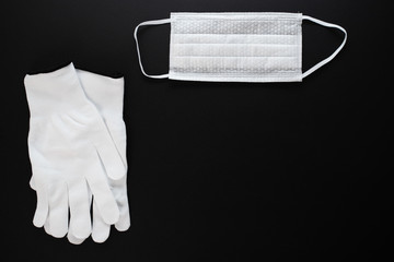 Coronavirus protection. White antibacterial medical mask and protective gloves on a black background with copyspace