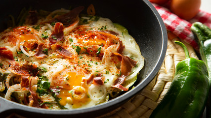 Eggs cooked in a pan with vegetables and iberico ham