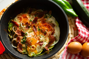 Eggs cooked in a pan with vegetables and iberico ham