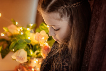Naklejka premium Portrait of a beautiful girl with a bouquet of color, bokeh and light from a garland