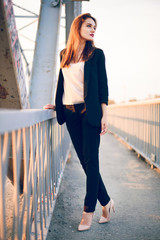 Model posing in trousers and a jacket on the bridge.