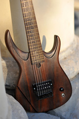 Fototapeta na wymiar Seven-string electric guitar made of dark wood. Background for music and creativity.