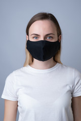 Woman in a black medical mask, isolated on a gray background