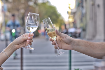 glasses of toast chin chin, hands with glasses of white wine in a street cafe
