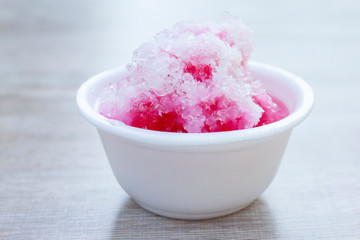 Shave ice in a white foam cup on wooden table, Sweets suitable for summer.