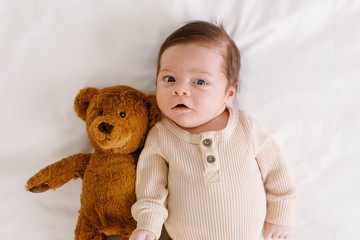 Baby with a bear toy on the bed