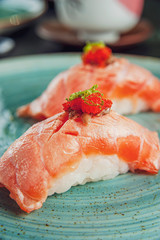 A pare of japanese salmon sushis on a rustic green dish