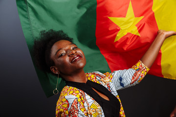 Young beautiful African fashion model with flag of Cameroon in traditional dress.