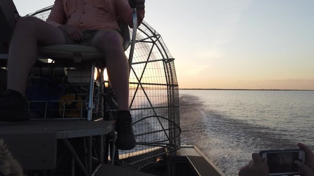 Woman Takes Picture With Cellphone Of Airboat Captain Boating Over Everglades At Sunset