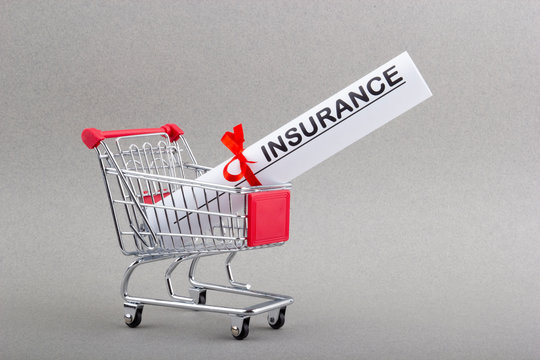 Paper Bundle With Word Insurance And Red Ribbon In Shopping Trolley.