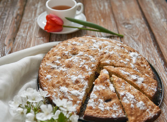 Homemade pie with cherries and apples white cup of tea on a dark rustic wooden board background. Rustic style food
