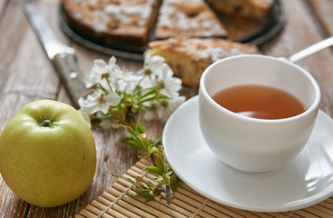 Homemade pie with cherries and apples white cup of tea on a dark rustic wooden board background. Rustic style food