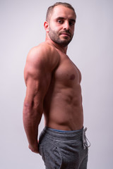 Profile view of muscular bearded man flexing arms shirtless