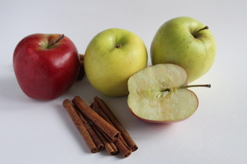 a few apples yellow green and red lie side by side on the table on a white background with cinnamon sticks there is a place to insert text