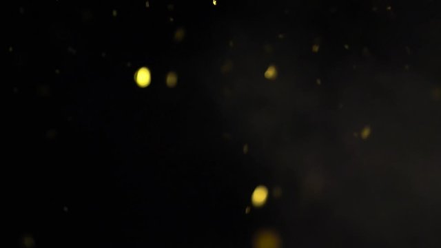 The yellow balloon bursts and releases sparkles and confetti into the aie, slow motion