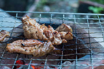 Roast pork on a metal grill using traditional charcoal grills.
