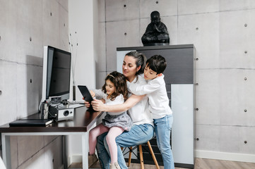 Middle-age mother with her children using digital tablet in workspace