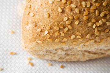 A close up of the crust of a dinner roll with sesame seeds.