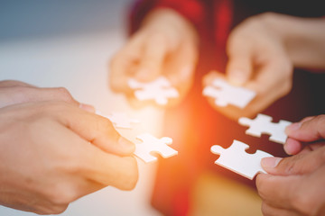Obraz na płótnie Canvas The hands of a variety of people including the Asian jigsaw puzzle And gather parts to find suitable partners to support teamwork to find common problem solving concepts, close-up perspectives