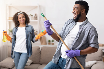 Tidying With Fun. Joyful Black Couple Fooling While Cleaning Flat Together