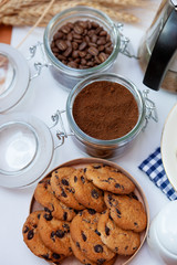 White cup of coffee and homemade round cookies with chocolate chips. Breakfast is on the table. Food at home. Still life. Coffee and coffee beans. An invigorating drink. Top view, flat lay.